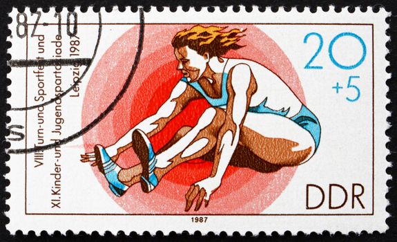 GDR - CIRCA 1987: a stamp printed in GDR shows Girls� Long Jump, 11th Children�s and Youths� Spartakiade, circa 1987