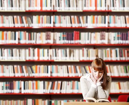 Portrait of a serious young student reading a book in a library 