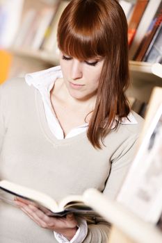 portrait of a young college student reading a book  in a library