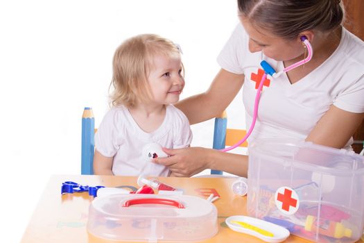 Mother and daughter playing doctor with stethoscope over white