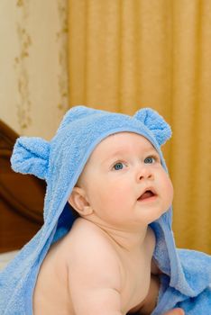 Smiling baby in blue towel on bed