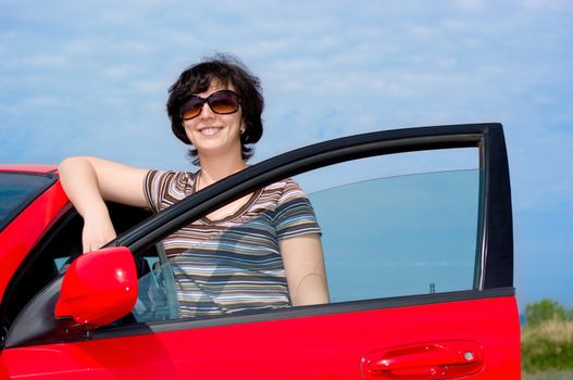 Young smiling woman with red car