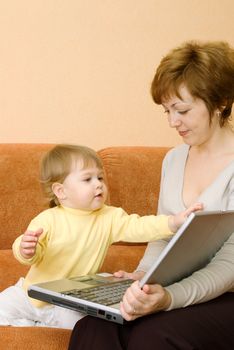 Small girl and mother with laptop at home