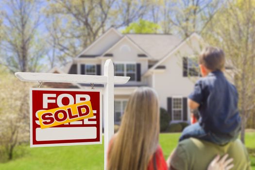 Curious Family Facing Sold For Sale Real Estate Sign and Beautiful New House.