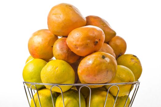 Delicious ripe oranges and mangoes piled up in a silver fruit bowl