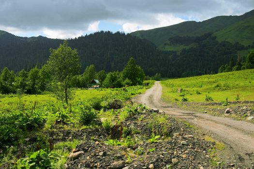 country road away in mountains on a background cloudy sky