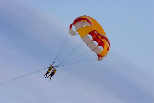 Parachute with soaring people on a background of the blue sky