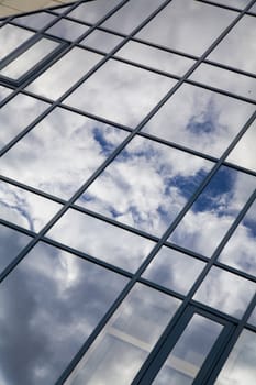 windows of skyscraper with reflections on a background cloudy sky