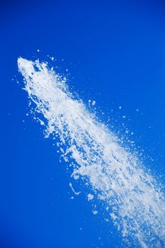 Fountain of pure brilliant water against a blue clear sky
