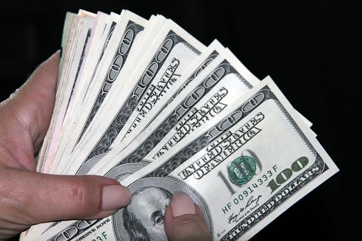 Woman hand holding american money on black background