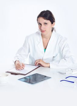 Young woman doctor  sitting on her desk , looking at camera