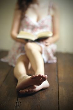 young woman reading a book on the old wooden floor