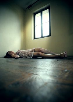 Dead woman lying on the wooden floor. Empty room