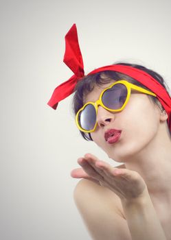 Young beautiful woman in sunglasses blow a kiss to you.