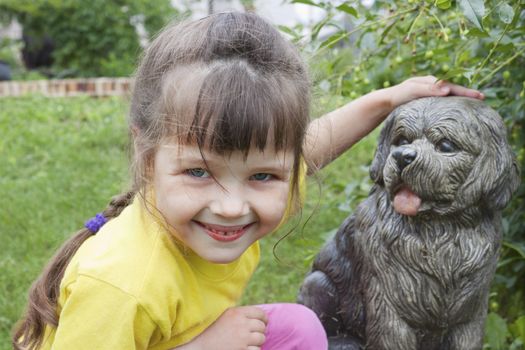 Girlie smiling near to concrete dog in garden