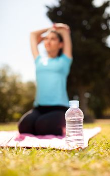 hydration concept bottle of water with woman stretching on background