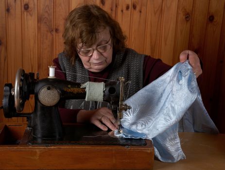 The old woman sews on the sewing machine