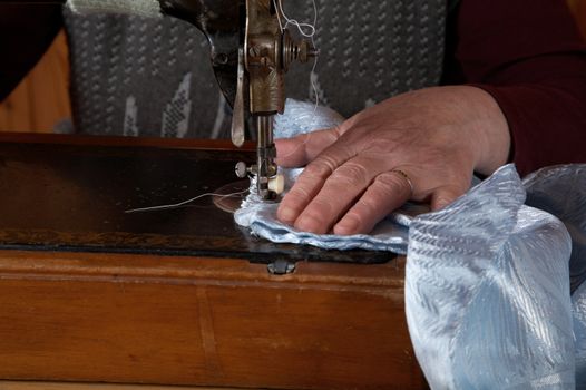 The old woman sews on the sewing machine