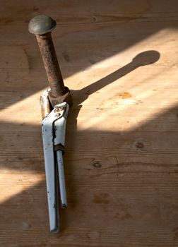 Adjustable spanner and rusty bolt with a nut on  wooden table