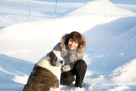 woman plays with a dog in the winter sunny day