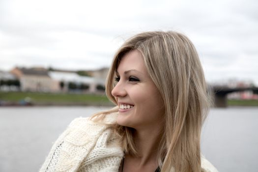 The smiling girl against the river in the cloudy afternoon