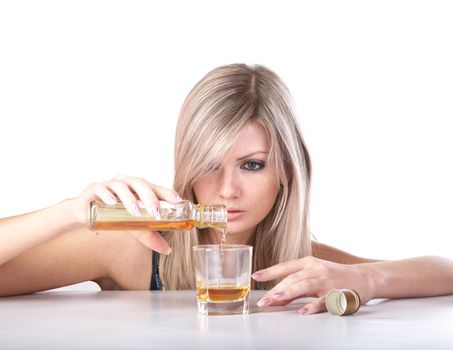 The girl pours whisky from  bottle in  glass on a white background