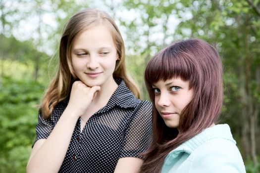 Two girls of the teenager in  spring afternoon against green foliage