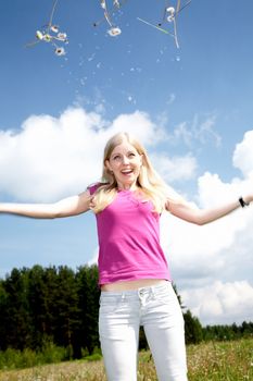 The girl scatters dandelions in the solar spring afternoon