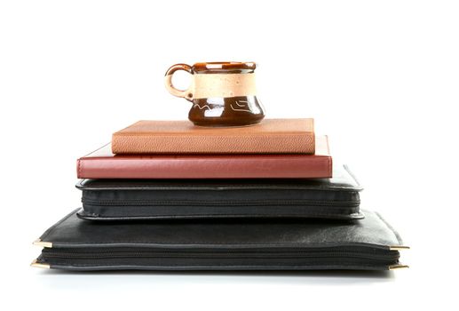 Pile of folders and organizers with a coffee cup on  white background