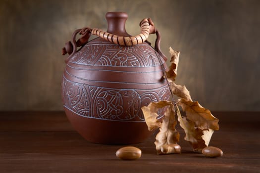 Still-life with jug and dry leaves of an oak on  table