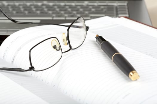 Organizer, glasses,pen and notebook on a desk