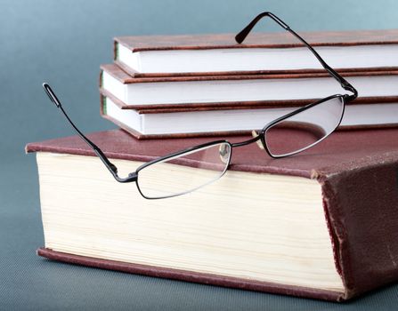 Pile of books and glasses on old thick volume