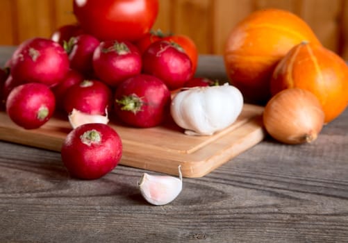 Onions garlic  garden radish on a table from unplaned boards