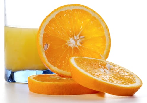 Segments of an orange and a glass of juice on a white background