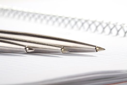 line of ball-point pens lays on a writing-book