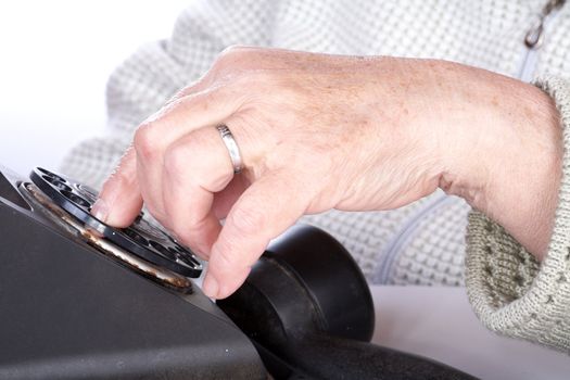 The hand  old woman dials  number of phone on a white background