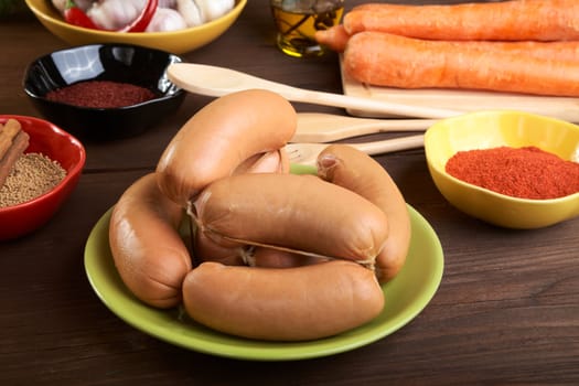 Sausages with spices and vegetables on an old wooden table