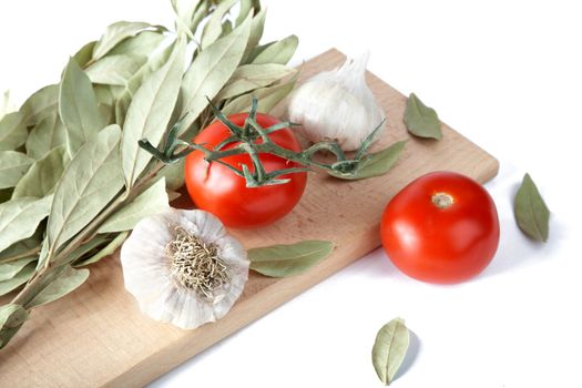 Tomatoes garlic and bay leaf branches on a white background