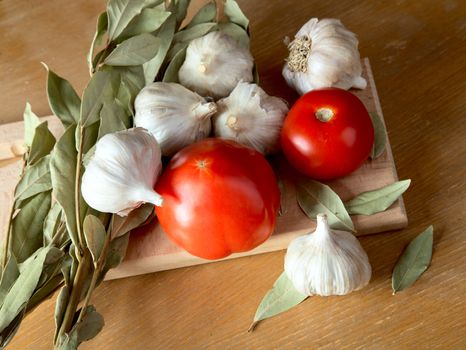Tomatoes garlic and a bay leaf on an old table