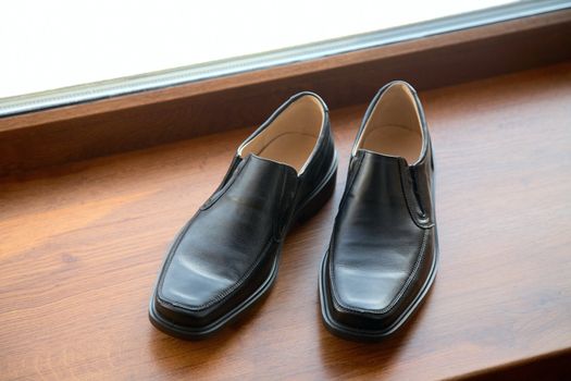 Black man's shoes stand on a window sill