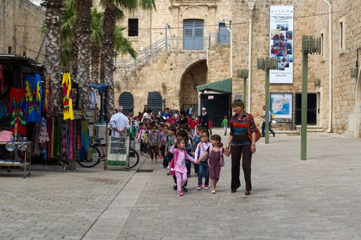 Little arabic girls holding one for another going to school in Akko, Israel