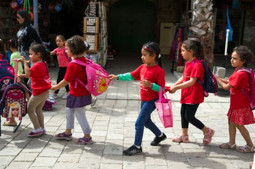 Little arabic girls holding one for another going to school in Akko, Israel