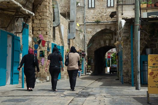 Three arab women going on the street in the old city of Akko, Israel