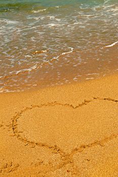 Heart shape symbol drawn in sand on a beach