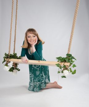 beautiful woman in a green dress on a swing