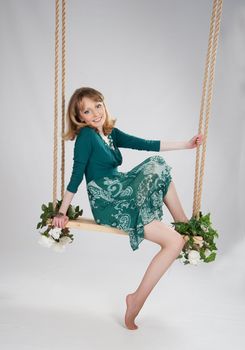 beautiful woman in a green dress on a swing