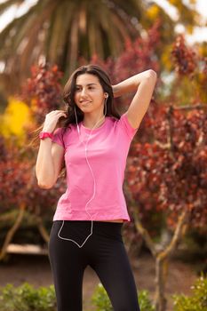 Young beautiful woman with sporty look enjoying with headphones outdoors