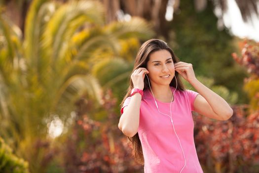 Young beautiful woman with sporty look enjoying with headphones outdoors