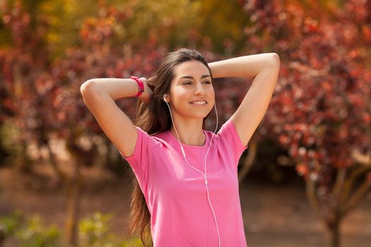 Young beautiful woman with sporty look enjoying with headphones outdoors