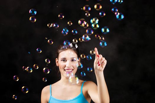 Happy girl and soap bubbles on the black background